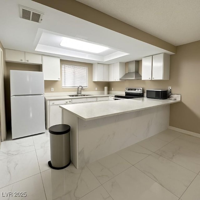 4420 Rich Dr Unit B, Las Vegas, NV 89102 - kitchen with freestanding refrigerator, stainless steel range with electric cooktop, wall chimney exhaust hood, light marble finish flooring, and a tray ceiling