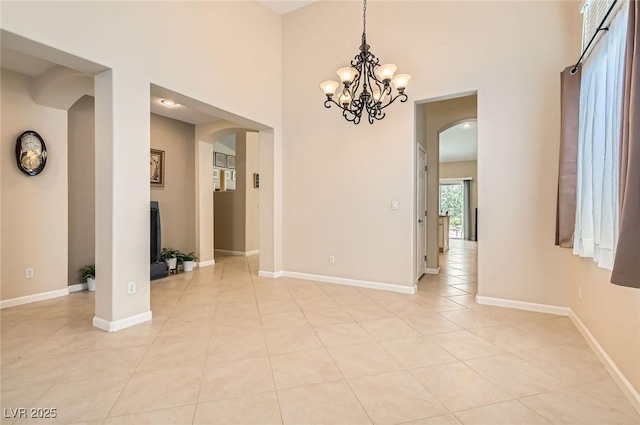 7559 Chambery Cove Ct, Las Vegas, NV 89123 - spare room with arched walkways, a chandelier, light tile patterned flooring, and a high ceiling