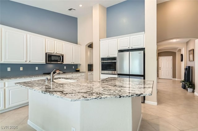 7559 Chambery Cove Ct, Las Vegas, NV 89123 - kitchen with appliances with stainless steel finishes, a high ceiling, arched walkways, and light tile patterned flooring