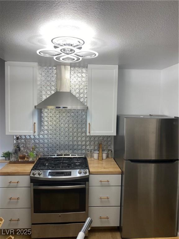 7885 W Flamingo Rd Unit 2129, Las Vegas, NV 89147 - kitchen featuring stainless steel appliances, wall chimney range hood, butcher block countertops, a textured ceiling, and backsplash