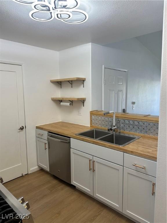 7885 W Flamingo Rd Unit 2129, Las Vegas, NV 89147 - kitchen with dishwasher, butcher block counters, light wood-style floors, open shelves, and a textured ceiling