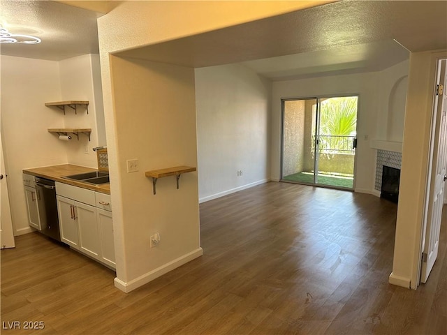 7885 W Flamingo Rd Unit 2129, Las Vegas, NV 89147 - kitchen with open shelves, white cabinets, dark wood-type flooring, a tile fireplace, and open floor plan