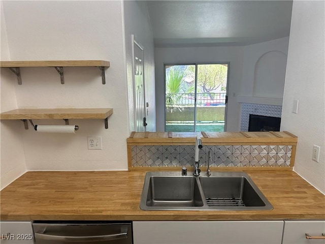 7885 W Flamingo Rd Unit 2129, Las Vegas, NV 89147 - kitchen with stainless steel dishwasher, butcher block counters, and a tile fireplace