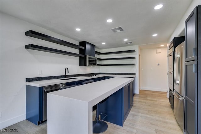 7132 Mission Hills Dr, Las Vegas, NV 89113 - kitchen with open shelves, appliances with stainless steel finishes, a center island, light countertops, and light wood finished floors