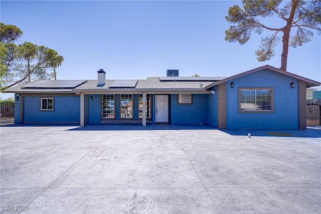 4490 W Warm Springs Rd, Las Vegas, NV 89118 - view of front of house featuring a chimney, roof mounted solar panels, and stucco siding