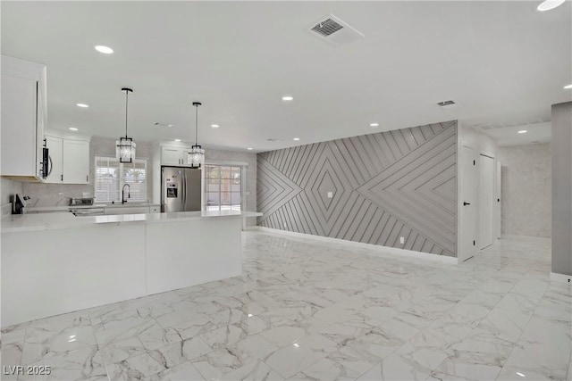 4490 W Warm Springs Rd, Las Vegas, NV 89118 - kitchen featuring stainless steel fridge with ice dispenser, light countertops, white cabinets, black microwave, and a peninsula