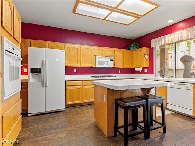1870 Desert Forest Way, Henderson, NV 89012 - kitchen with white appliances, tile counters, a center island, dark wood-style flooring, and a breakfast bar