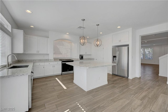 10325 Quartz Reef Ct, Las Vegas, NV 89141 - kitchen featuring stainless steel appliances, a chandelier, a center island, light stone countertops, and white cabinets