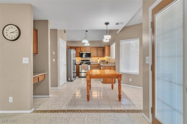 7720 Leavorite Dr, Las Vegas, NV 89128 - kitchen featuring stainless steel appliances, brown cabinetry, light tile patterned floors, and decorative light fixtures