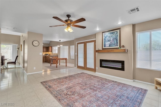 7720 Leavorite Dr, Las Vegas, NV 89128 - tiled living area featuring a ceiling fan, plenty of natural light, recessed lighting, a glass covered fireplace, and french doors