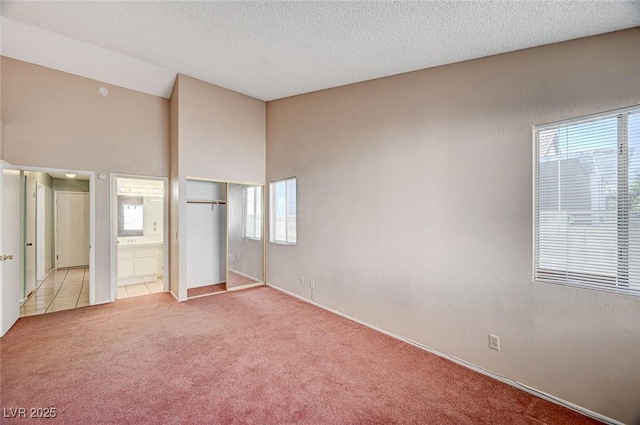 1950 Turtlerock St, Las Vegas, NV 89142 - unfurnished bedroom featuring light carpet, ensuite bath, vaulted ceiling, a textured ceiling, and a closet
