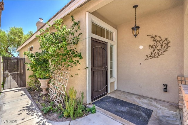 1869 Desert Forest Way, Henderson, NV 89012 - property entrance with stucco siding, a gate, and a chimney