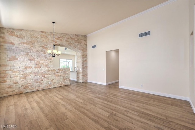 1869 Desert Forest Way, Henderson, NV 89012 - unfurnished dining area with a chandelier, wood finished floors, ornamental molding, and arched walkways