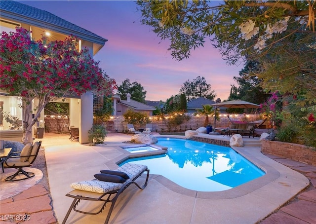 3004 Astoria Pines Cir, Las Vegas, NV 89107 - pool at dusk featuring a patio area, a fenced backyard, a pool with connected hot tub, and outdoor dining space