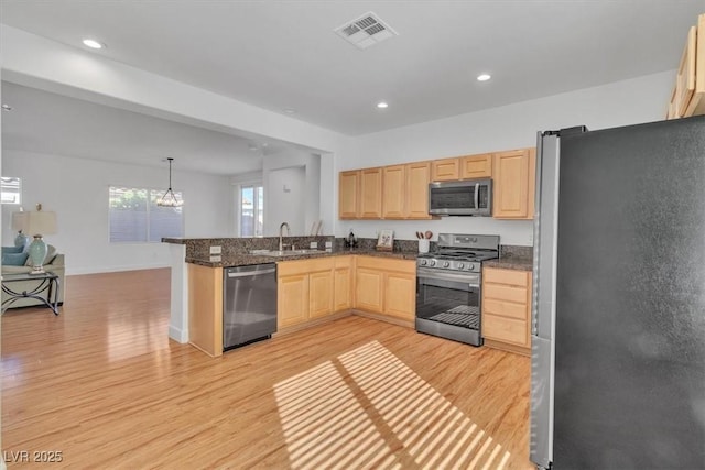 11253 Revelry Ln, Las Vegas, NV 89138 - kitchen with appliances with stainless steel finishes, light brown cabinetry, light wood-style flooring, a peninsula, and a chandelier