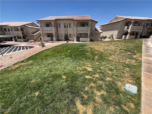 435 Mesa Blvd Unit 202, Mesquite, NV 89027 - back of house with stairs, a tiled roof, a lawn, and stucco siding