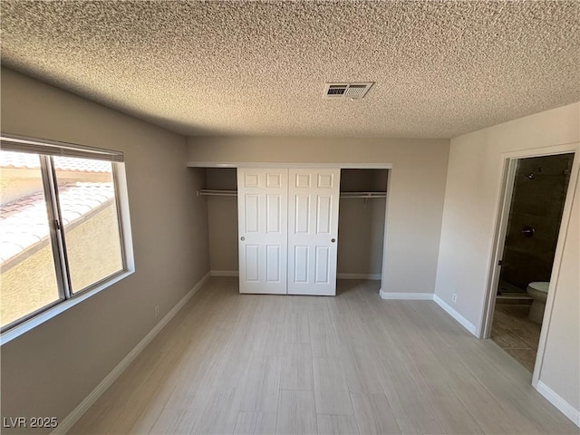 435 Mesa Blvd Unit 202, Mesquite, NV 89027 - unfurnished bedroom with light wood-style flooring, a textured ceiling, a closet, and connected bathroom
