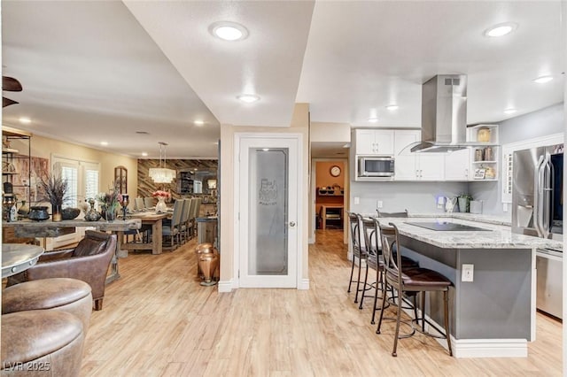 5260 N Jones Blvd, Las Vegas, NV 89130 - kitchen with stainless steel appliances, island range hood, a breakfast bar area, open floor plan, and light wood-style floors