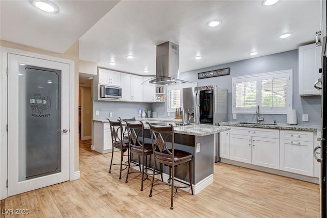 5260 N Jones Blvd, Las Vegas, NV 89130 - kitchen featuring island exhaust hood, white cabinets, appliances with stainless steel finishes, a kitchen bar, and light stone countertops