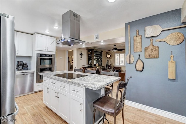 5260 N Jones Blvd, Las Vegas, NV 89130 - kitchen featuring island range hood, stainless steel appliances, a breakfast bar area, light wood-style flooring, and recessed lighting