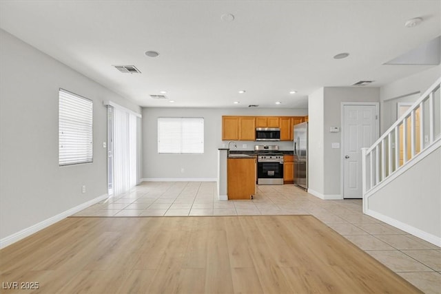 1109 Claire Rose Ave, Las Vegas, NV 89183 - kitchen featuring appliances with stainless steel finishes, open floor plan, light tile patterned floors, brown cabinetry, and dark countertops