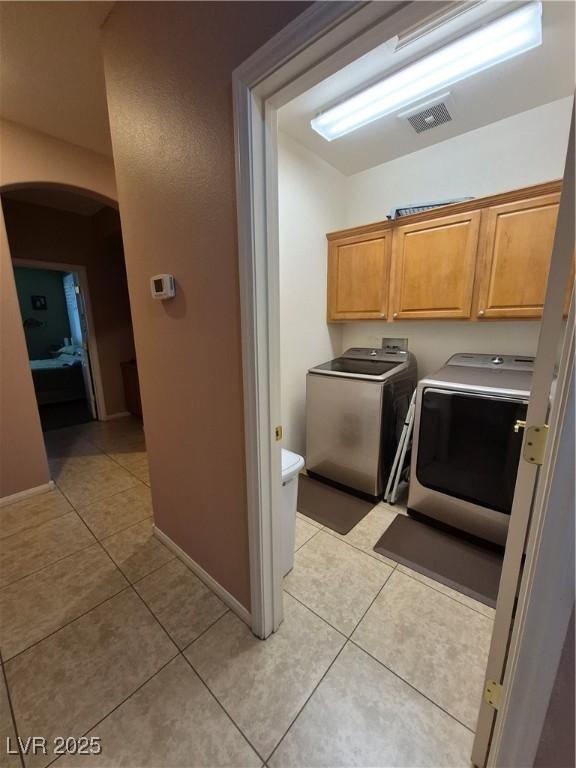 6009 Arbor Crest St, North Las Vegas, NV 89081 - laundry area featuring arched walkways, washer and clothes dryer, light tile patterned flooring, and cabinet space