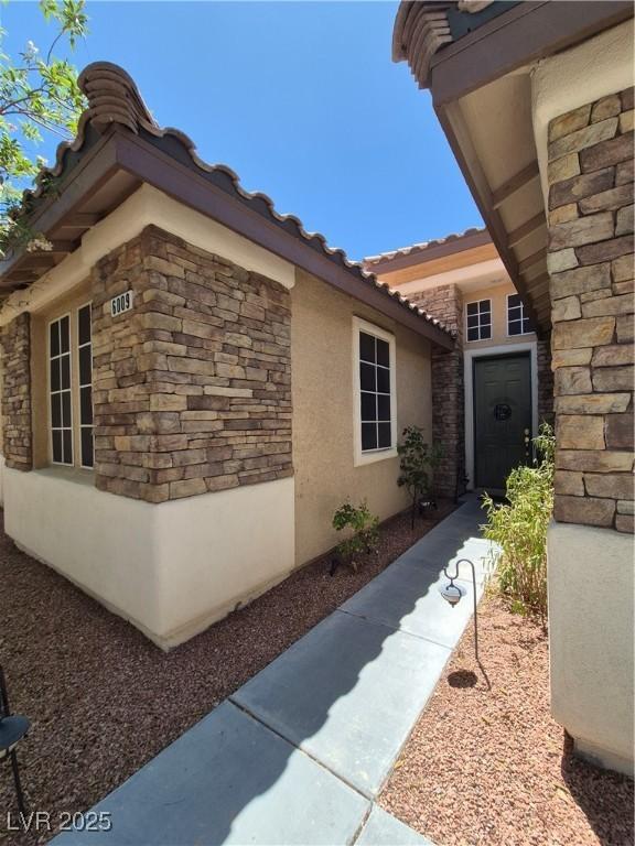 6009 Arbor Crest St, North Las Vegas, NV 89081 - view of home's exterior featuring stone siding, stucco siding, and a tile roof