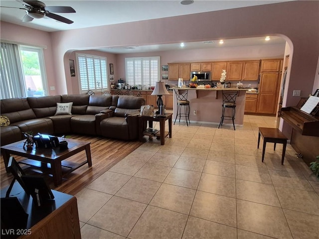6009 Arbor Crest St, North Las Vegas, NV 89081 - living room with arched walkways, light tile patterned floors, a ceiling fan, and plenty of natural light