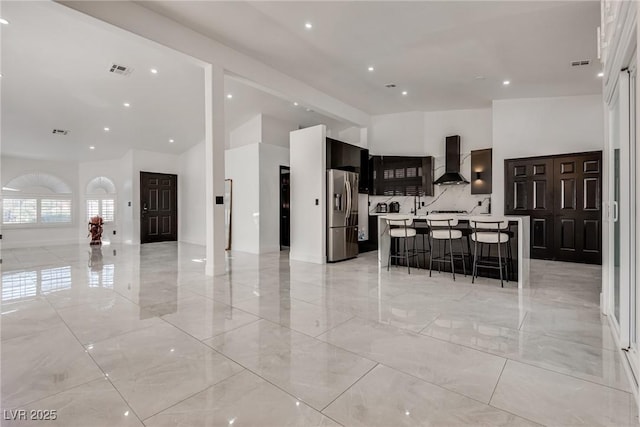 825 Royal Moon Ave, Las Vegas, NV 89123 - kitchen with wall chimney range hood, stainless steel refrigerator with ice dispenser, high vaulted ceiling, open floor plan, and a breakfast bar