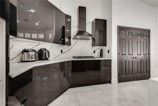 825 Royal Moon Ave, Las Vegas, NV 89123 - kitchen with wall chimney exhaust hood, modern cabinets, backsplash, stainless steel gas cooktop, and light stone counters