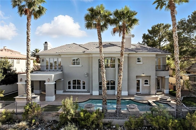 9408 Players Canyon Ct, Las Vegas, NV 89144 - back of property featuring a balcony, a chimney, a patio area, stucco siding, and a pool with connected hot tub
