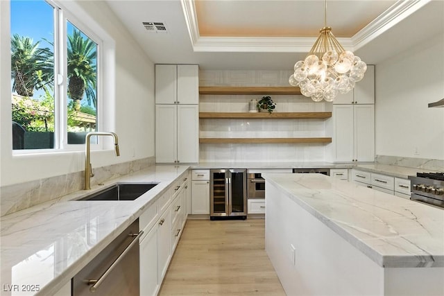9408 Players Canyon Ct, Las Vegas, NV 89144 - kitchen with wine cooler, appliances with stainless steel finishes, a raised ceiling, white cabinetry, and light wood-type flooring