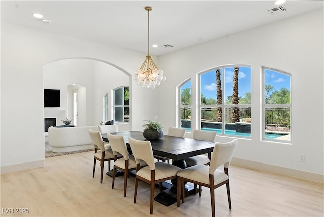 9408 Players Canyon Ct, Las Vegas, NV 89144 - dining room featuring light wood-style floors, recessed lighting, a glass covered fireplace, arched walkways, and a chandelier