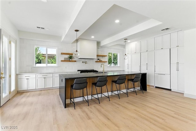 9408 Players Canyon Ct, Las Vegas, NV 89144 - kitchen with open shelves, light wood finished floors, tasteful backsplash, white cabinets, and a kitchen breakfast bar