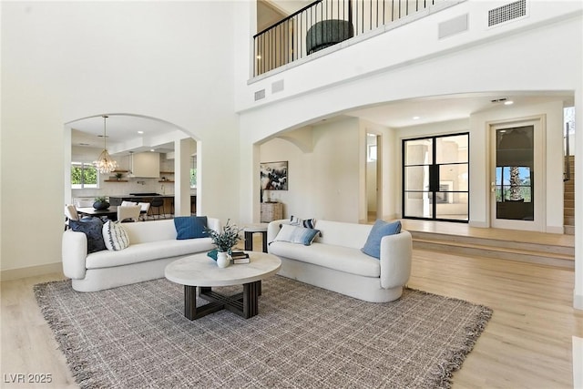 9408 Players Canyon Ct, Las Vegas, NV 89144 - living area featuring arched walkways, wood finished floors, a chandelier, a towering ceiling, and recessed lighting