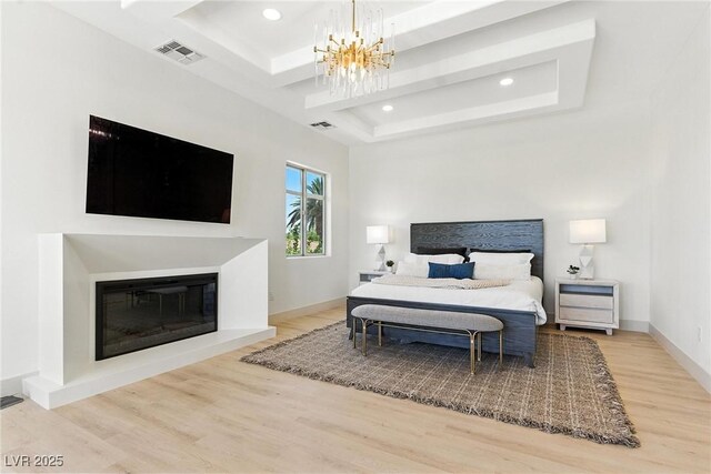 9408 Players Canyon Ct, Las Vegas, NV 89144 - bedroom featuring wood finished floors, a chandelier, recessed lighting, a glass covered fireplace, and a raised ceiling