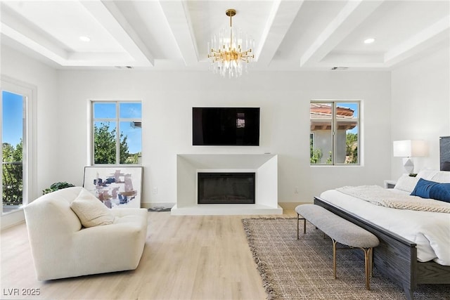 9408 Players Canyon Ct, Las Vegas, NV 89144 - bedroom featuring a chandelier, wood finished floors, a tray ceiling, a glass covered fireplace, and recessed lighting
