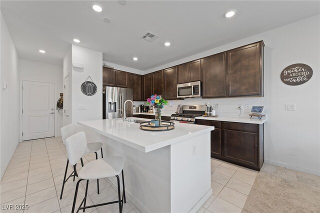 2732 Roman Palm Rd, North Las Vegas, NV 89086 - kitchen featuring appliances with stainless steel finishes, light tile patterned flooring, a breakfast bar, dark brown cabinets, and recessed lighting