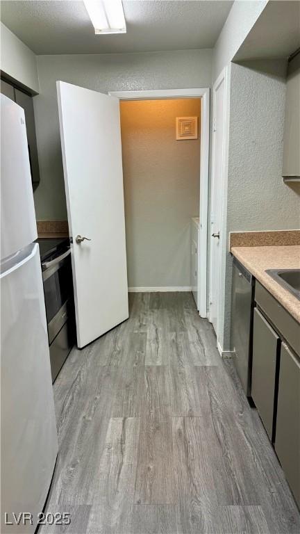8101 W Flamingo Rd Unit 2110, Las Vegas, NV 89147 - kitchen with stainless steel appliances, light wood-type flooring, light countertops, and gray cabinets