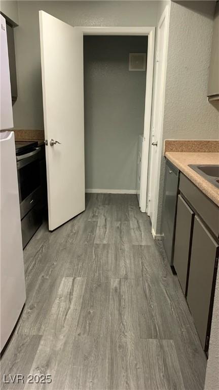8101 W Flamingo Rd Unit 2110, Las Vegas, NV 89147 - kitchen with appliances with stainless steel finishes, gray cabinets, wood finished floors, and light countertops