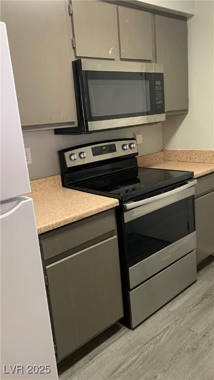 8101 W Flamingo Rd Unit 2110, Las Vegas, NV 89147 - kitchen with appliances with stainless steel finishes, gray cabinets, light countertops, and light wood finished floors