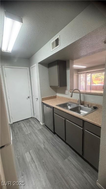 8101 W Flamingo Rd Unit 2110, Las Vegas, NV 89147 - kitchen featuring dishwasher, wood finished floors, light countertops, and a textured ceiling