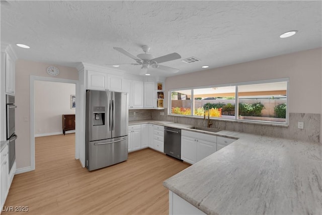 3753 Meadowcrest Dr, Las Vegas, NV 89121 - kitchen with stainless steel appliances, white cabinets, light wood-type flooring, recessed lighting, and ceiling fan