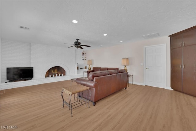 3753 Meadowcrest Dr, Las Vegas, NV 89121 - living room with a brick fireplace, light wood-style floors, a ceiling fan, recessed lighting, and a textured ceiling