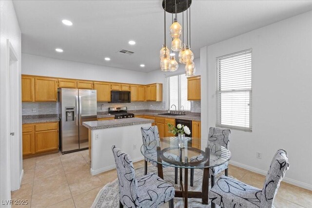 820 Peach Ave, North Las Vegas, NV 89032 - kitchen with black appliances, light tile patterned flooring, backsplash, hanging light fixtures, and a kitchen island