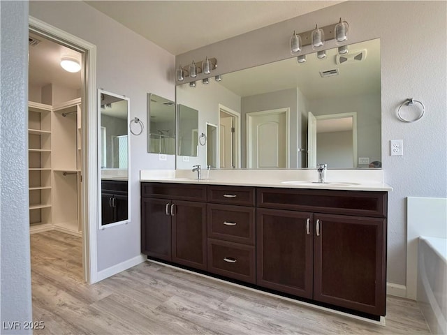 9604 Vital Crest St, Las Vegas, NV 89123 - bathroom with double vanity, a tub to relax in, wood finished floors, and a spacious closet