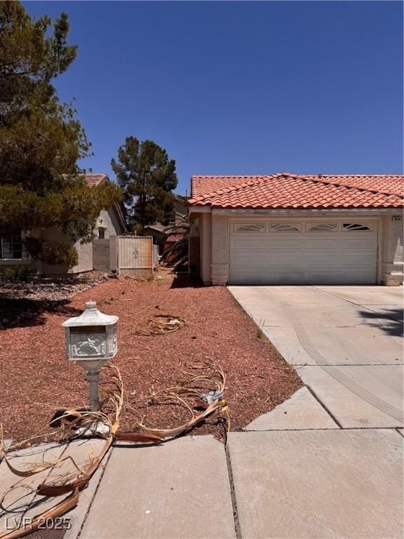 3644 Valley Dr, North Las Vegas, NV 89032 - view of front facade featuring a tiled roof, driveway, stucco siding, a gate, and an attached garage