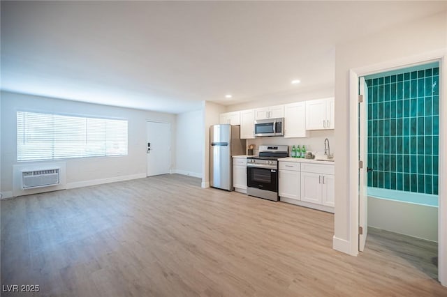 4600 University Center Dr Unit 72, Las Vegas, NV 89119 - kitchen featuring appliances with stainless steel finishes, a wall unit AC, light wood-style flooring, white cabinetry, and recessed lighting