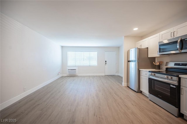 4600 University Center Dr Unit 72, Las Vegas, NV 89119 - kitchen featuring appliances with stainless steel finishes, an AC wall unit, light wood-type flooring, white cabinetry, and light countertops