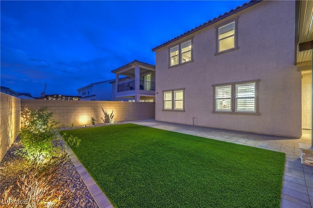 8984 Rolling Pietra St, Las Vegas, NV 89166 - yard at night featuring a fenced backyard, a patio, and a balcony